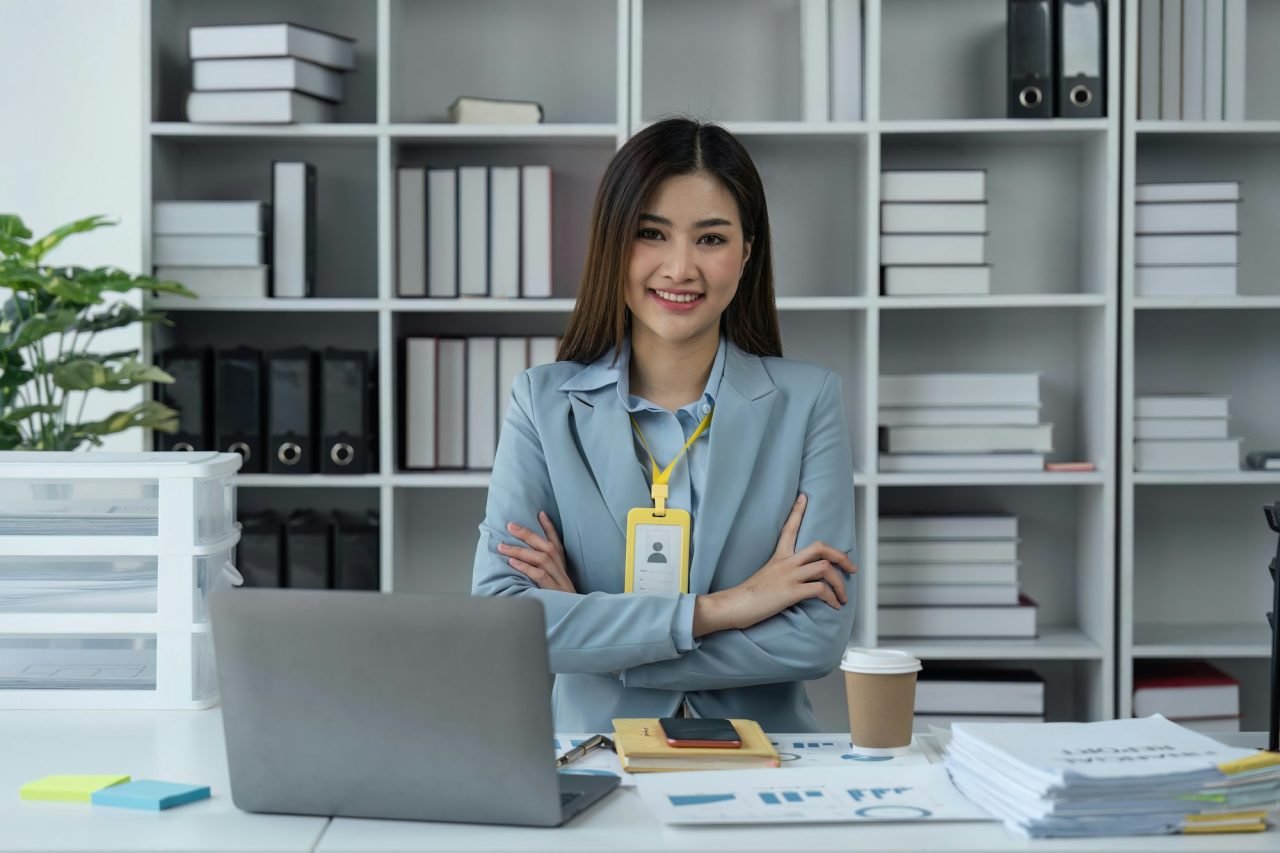 Business woman portrait and smile at desk in office for paperwork, laptop. Happy business young