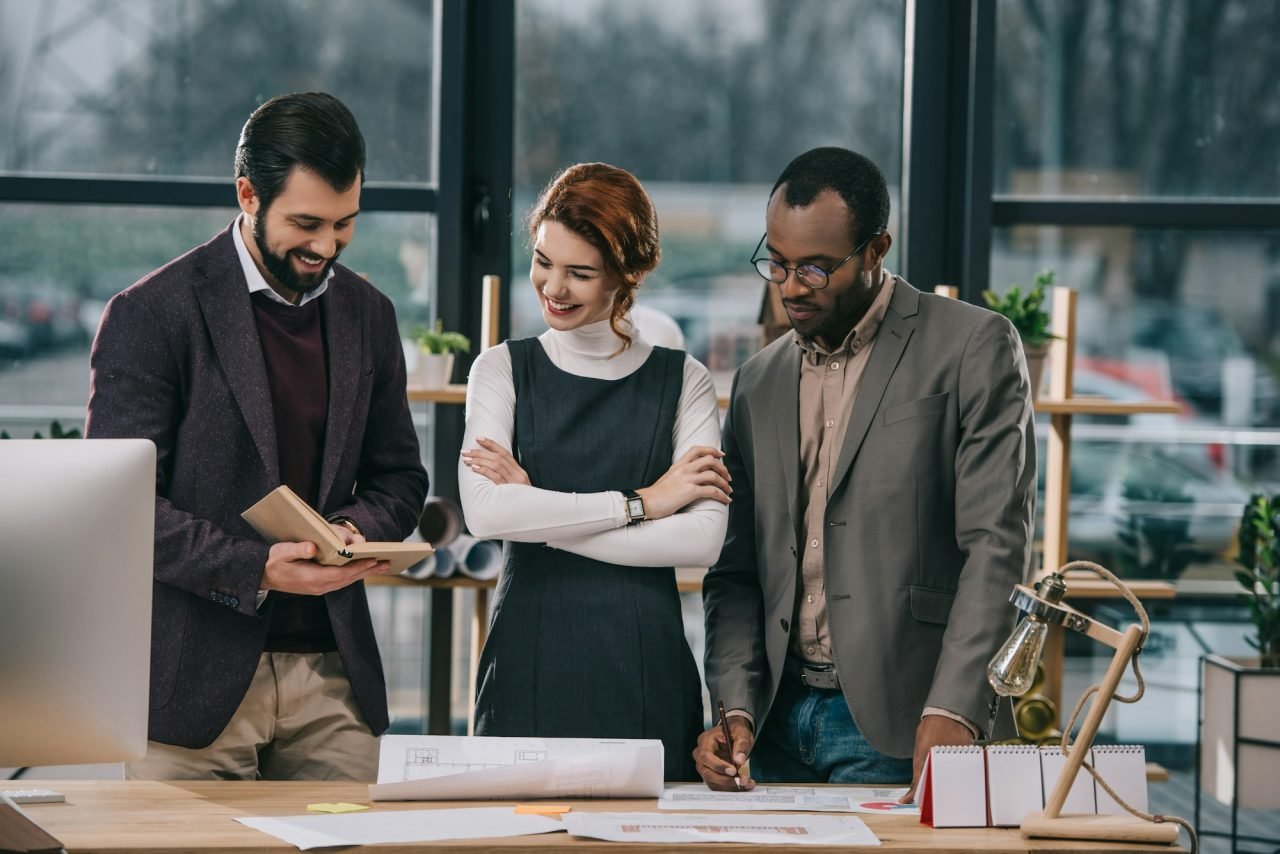 multiethnic architects discussing work in modern office