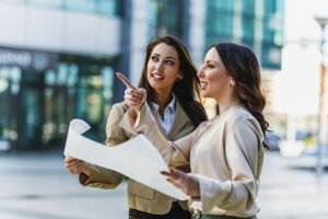 Two Business Woman Examining Building Plans Outside An Office