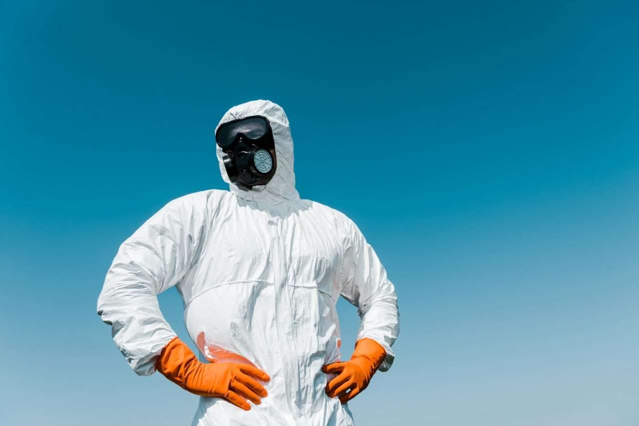 exterminator in protective mask and uniform standing with hands on hips