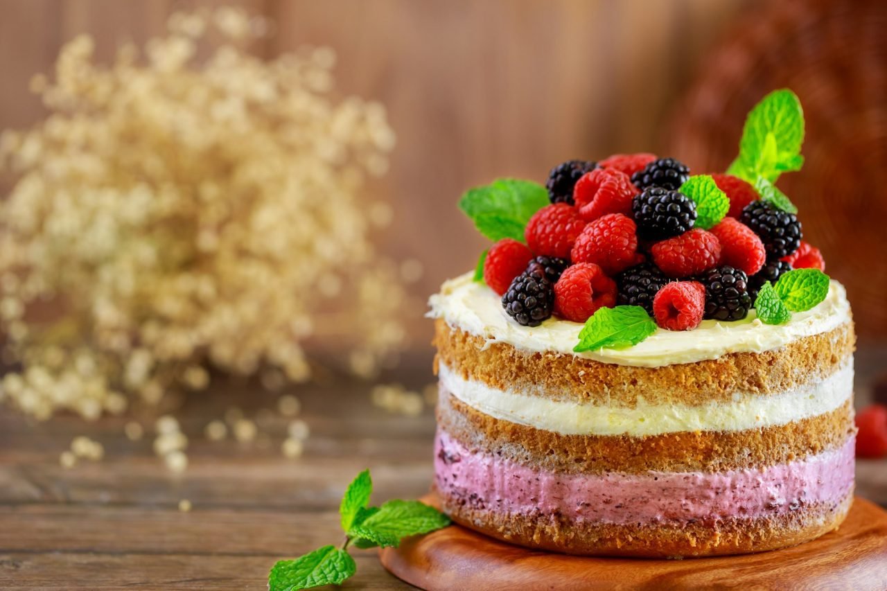 Fresh raspberries and blackberries decorate homemade berry cake.