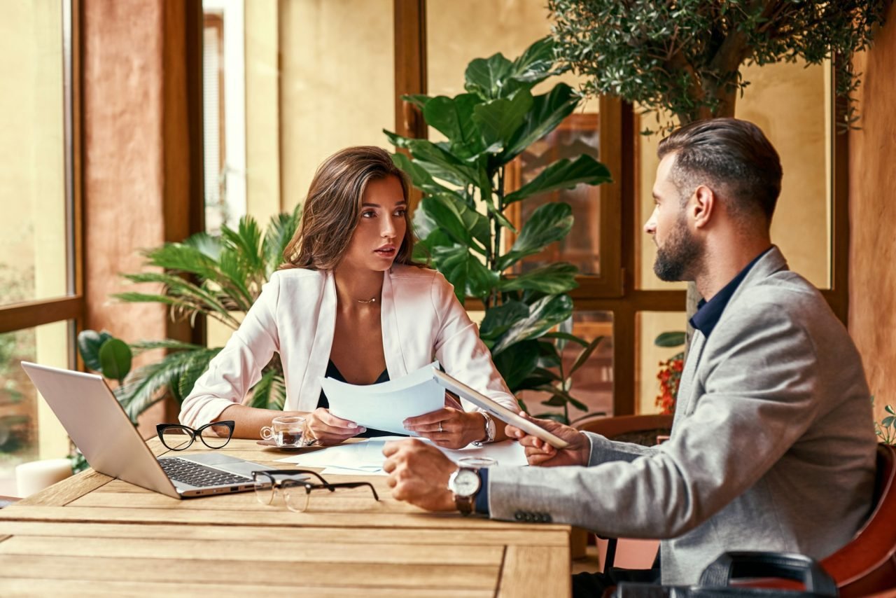 Business lunch. Business people sitting at table at restaurant looking at each other discussing