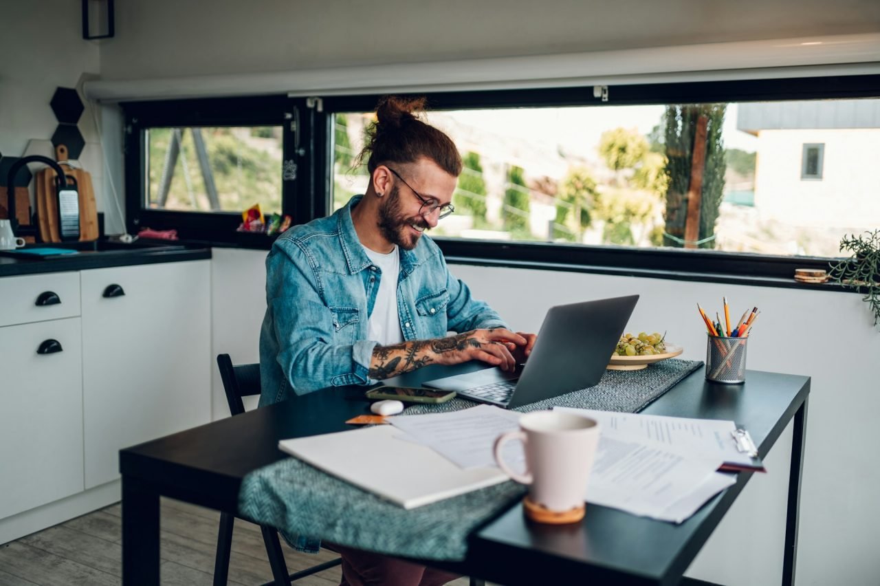 Young business man working at home with laptop and papers on desk