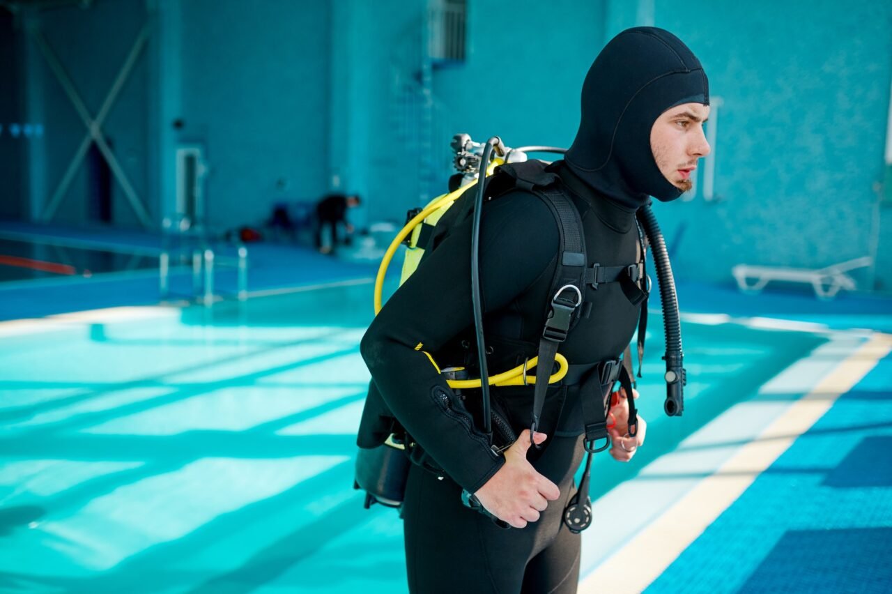 Male diver in scuba suit prepares for dive, diving
