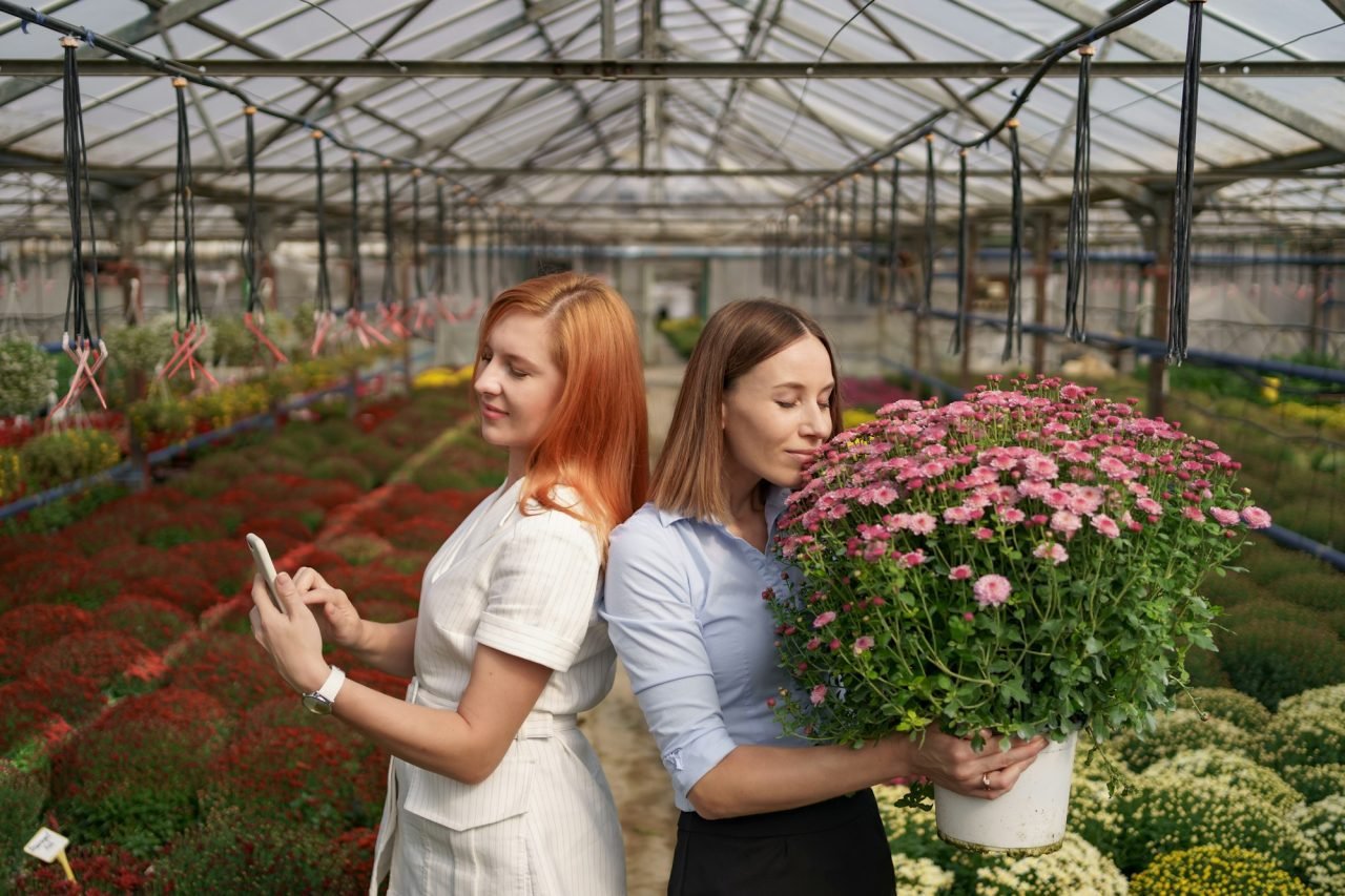 Smiling women posing with flowers in a greenhouse