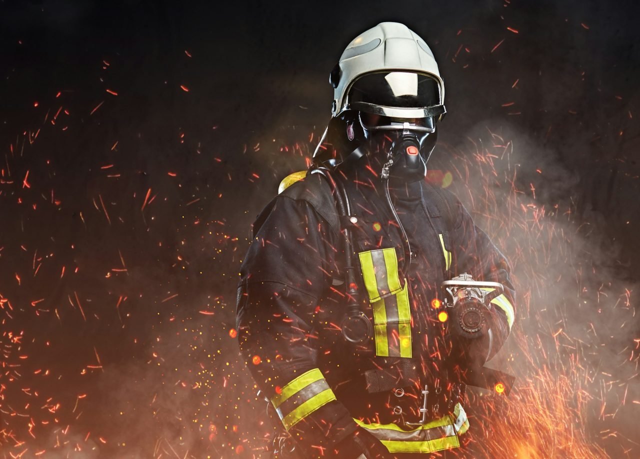 A firefighter dressed in a uniform in a studio.