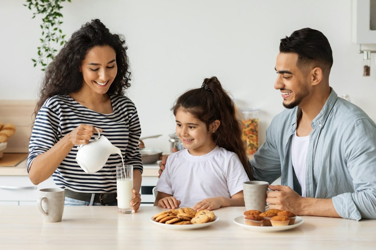 Loving mother pouring milk for her cute little daughter
