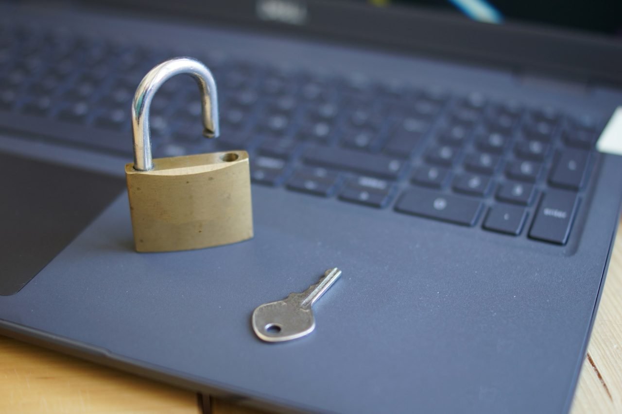 Closeup shot of an open padlock with a key on a laptop keyboard