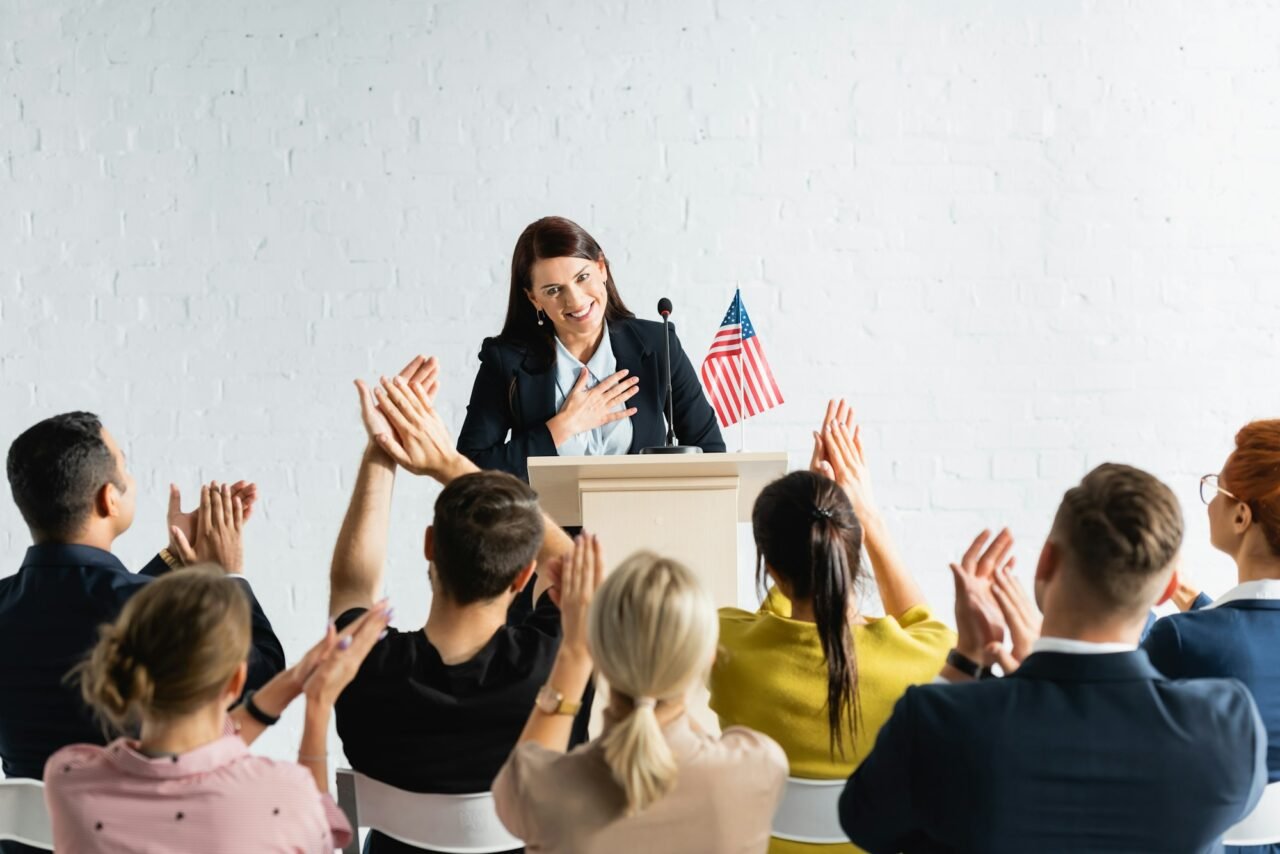 grateful candidate holding hand on chest while standing in front of applauding voters in conference