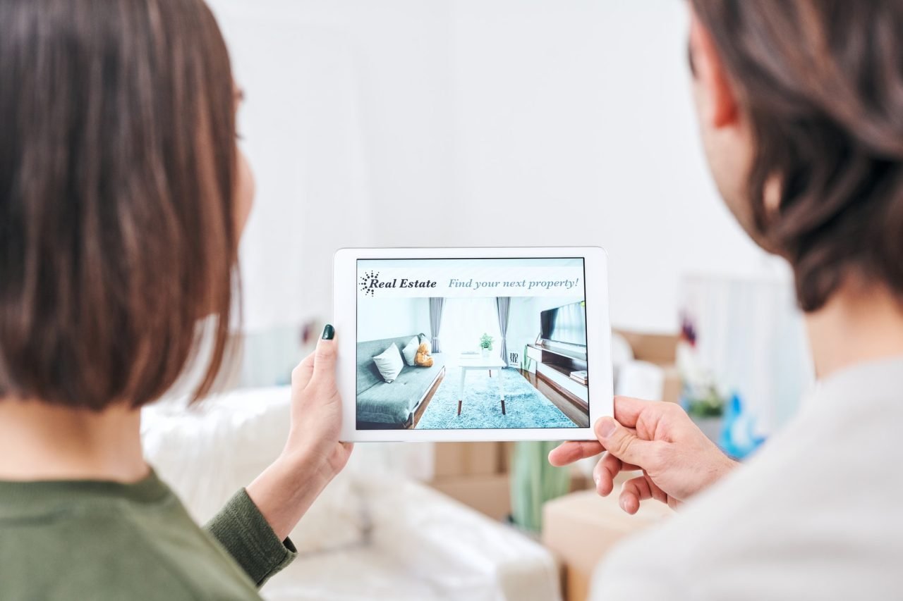 Young couple holding tablet with advertisement of real estate on sale