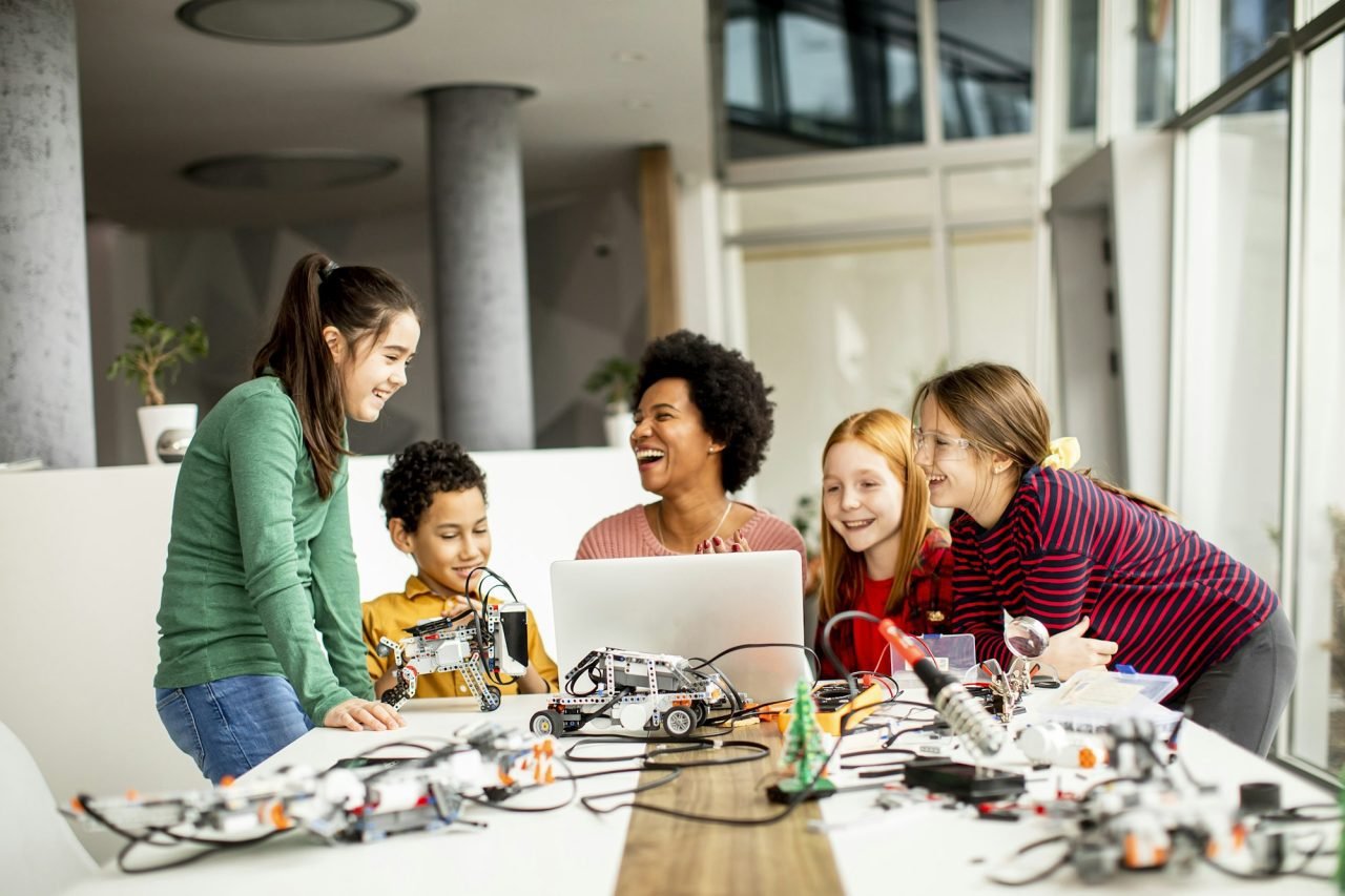 Group of happy kids with their African American female science teacher