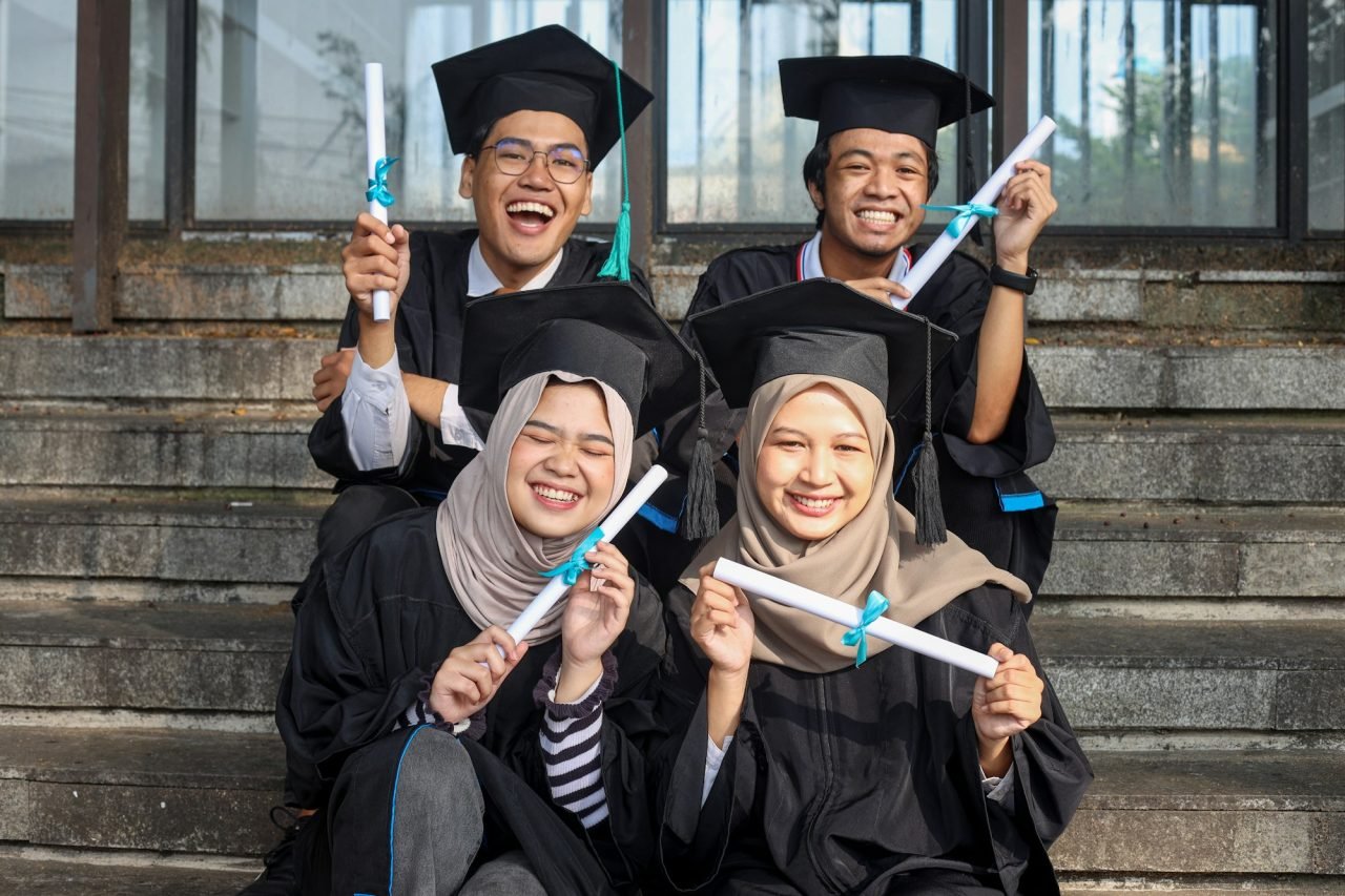 Group of young diverse students in graduation clothes feeling excited showing diploma