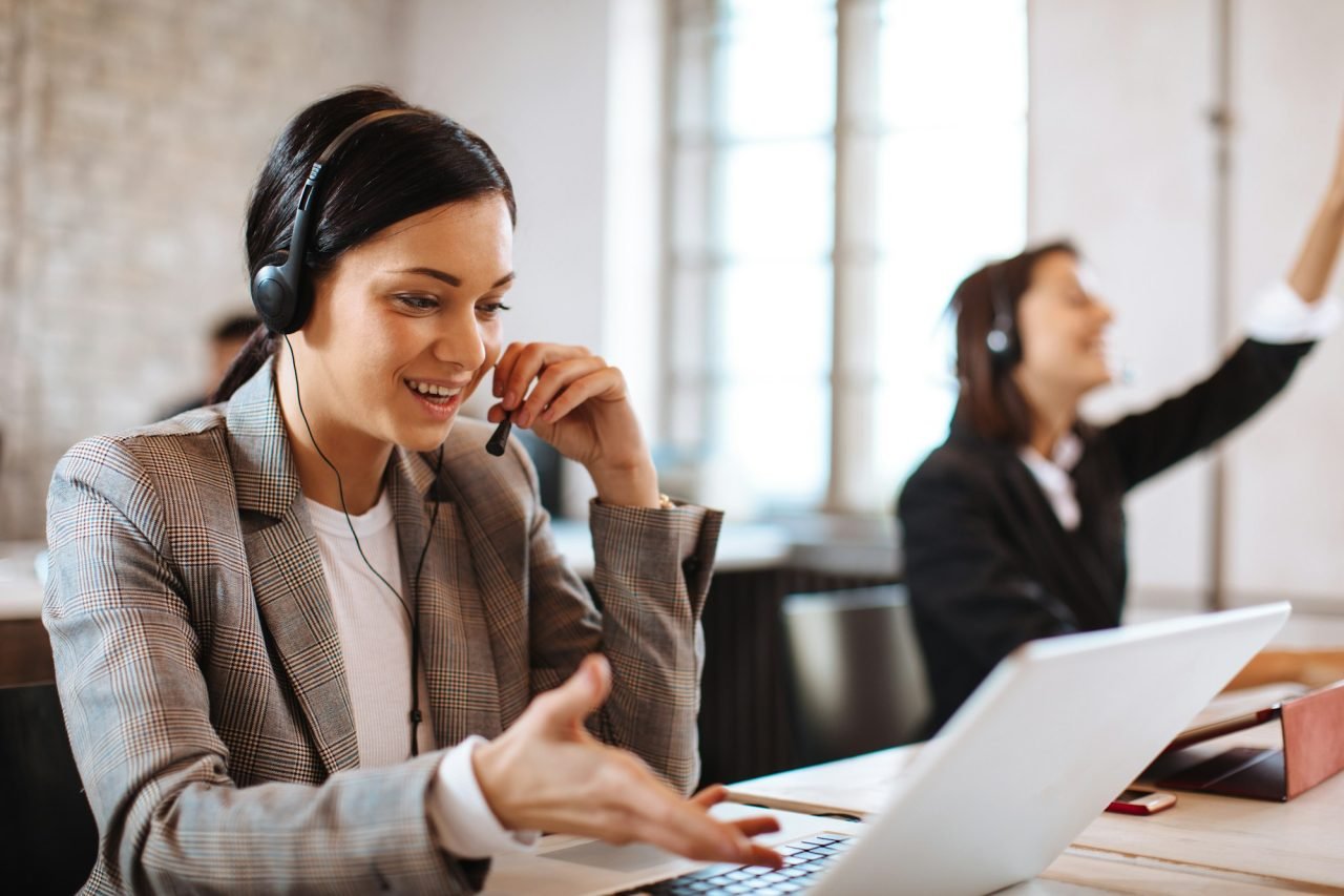 Beautiful female customer service talking on the headset with client and smiling
