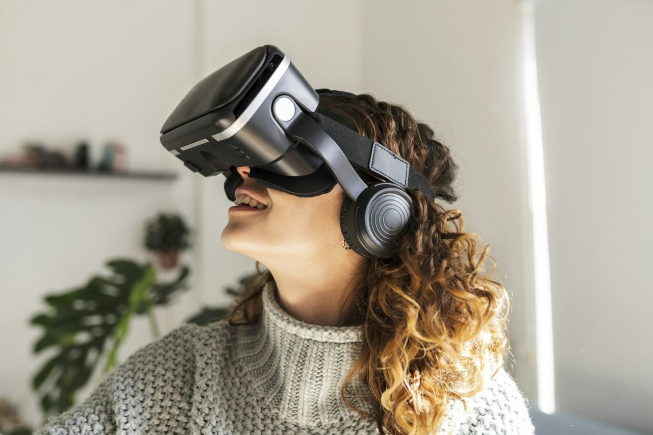 curly hair woman wearing virtual reality glasses at home