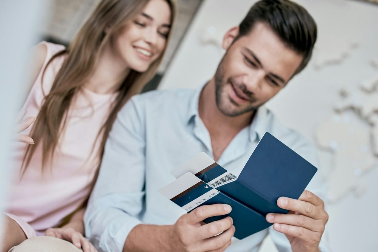 Young man smiling and reviwing tickets, passport with visa